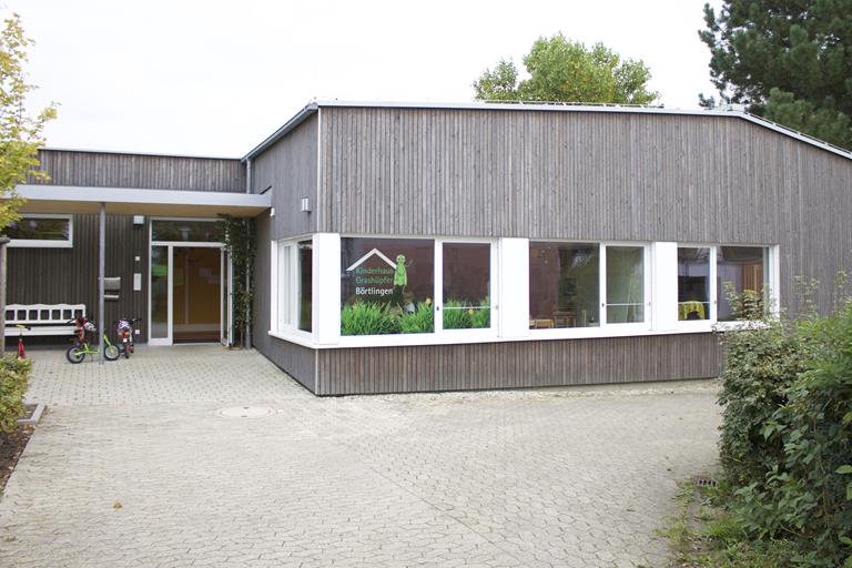 Ein Foto des Kinderhauses Grashüpfer in Börtlingen. Es handelt sich um ein mit Holz verkleidetes, einstöckiges Gebäude.